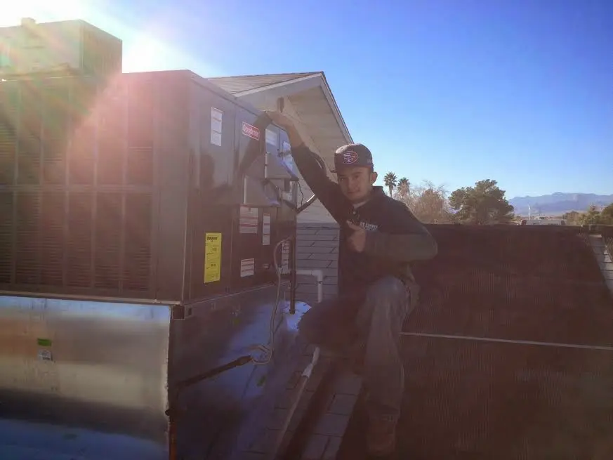 HVAC technician performing AC Tune-Up on a rooftop unit in Manlius